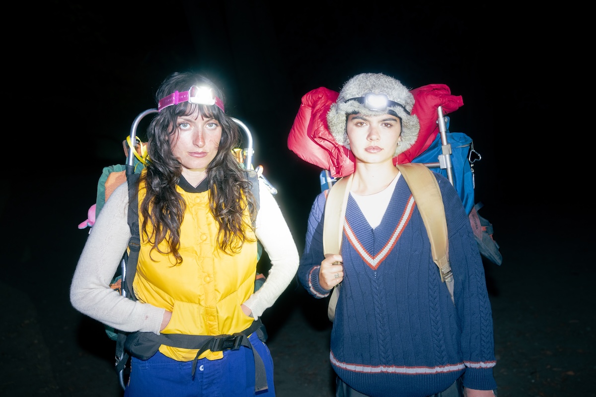 Indie duo The Army, The Navy wearing headlamps and large hiking backpacks outdoors at night for a high-contrast flash press portrait.